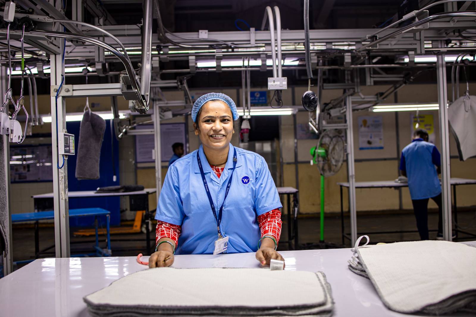 Textile worker standing at a garment finishing station