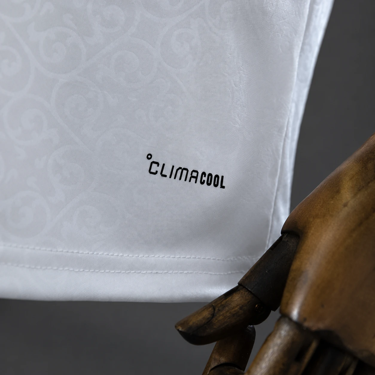 Close-up of white football jersey fabric, lower hem stitching and garment marking
