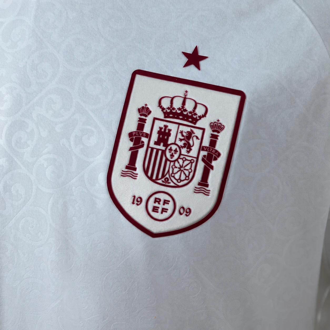 Close-up of the Spain football crest on patterned white jersey fabric